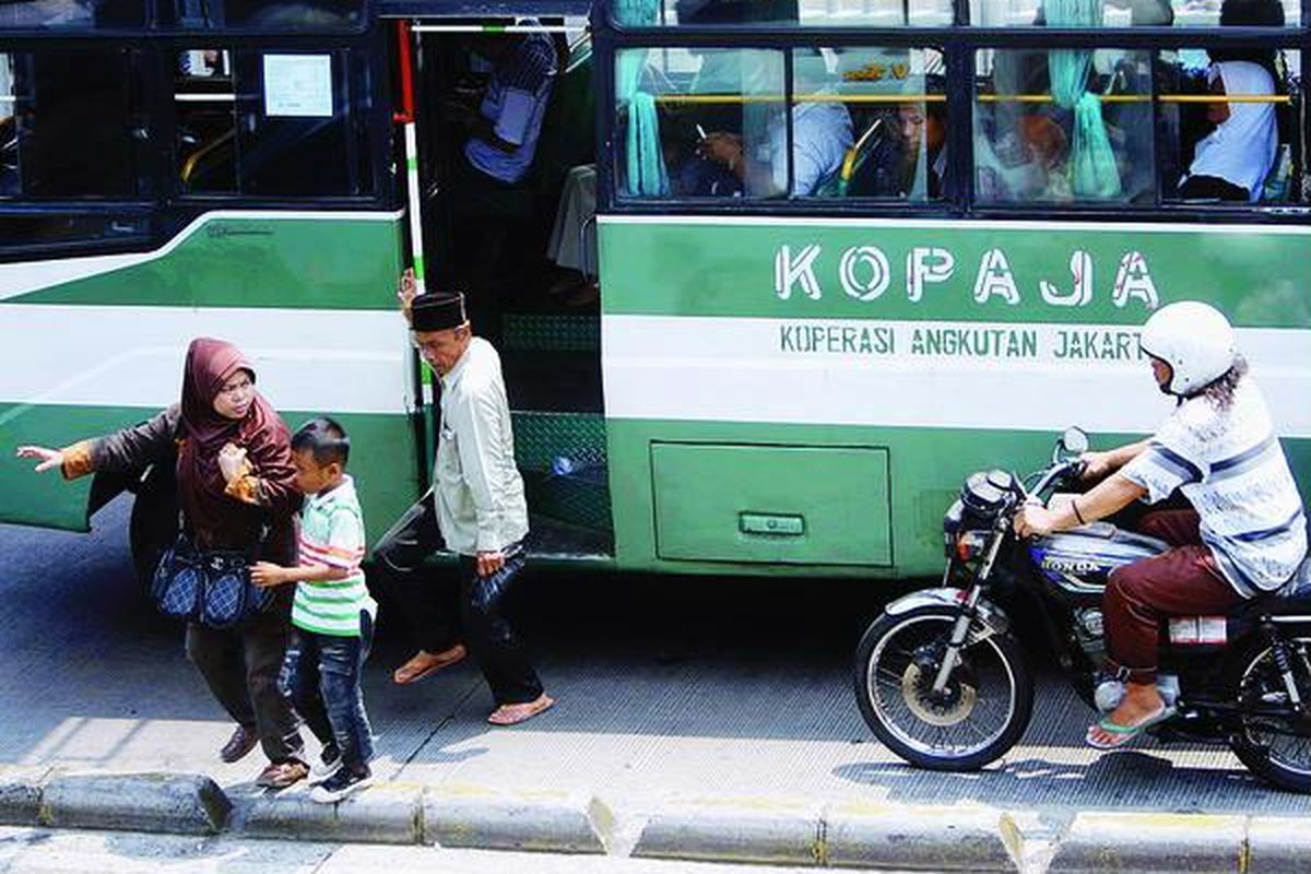 Kopaja menurunkan penumpang di tengah jalur bus transjakarta di Jalan Matraman Raya, Jakarta Timur, Selasa (23/10). Selain peremajaan armada, pengemudi angkutan umum juga harus dididik dan didata sehingga tidak membahayakan penumpang saat bertugas.
