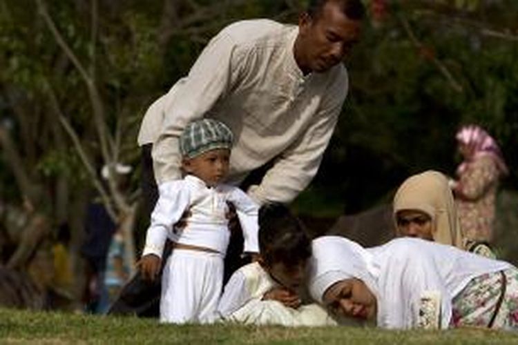 Warga melihat tulisan pada batu nisan seusai berdoa dan menabur bunga di kuburan massal korban gempa dan tsunami, Ulee Lheue, Kecamatan Meuraxa, Banda Aceh, dalam peringatan sembilan tahun tsunami Aceh, Kamis (26/12/2013). Gempa dan tsunami pada 26 Desember 2004 silam menyebabkan sekitar 230.000 korban meninggal serta ratusan ribu bangunan rusak.