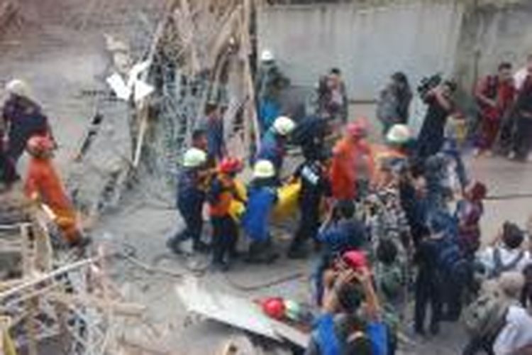 Petugas evakuasi mengangkat jasad korban dari timbunan jembatan penghubung Gedung Arsip dan Perpustakaan DKI Jakarta di Taman Ismail Marzuki, Menteng, Jakarta Pusat, yang ambruk pada Jumat (31/10/2014) pagi.