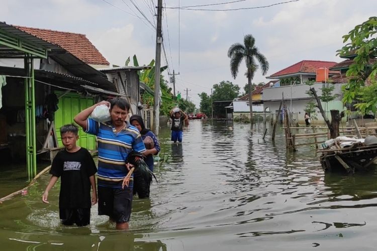 Warga dukuh Kedung Banteng, Desa Wonorejo nampak melintas di banjir yang masih menggenang di pemukiman, Selasa (20/2/2024). (KOMPAS.COM/NUR ZAIDI)