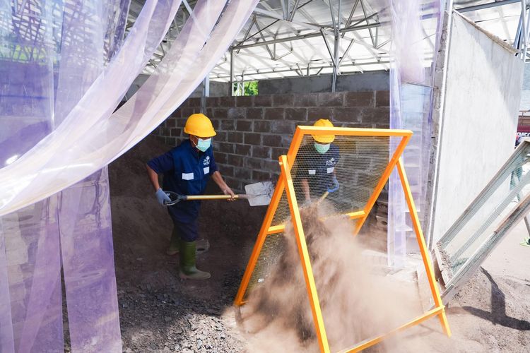 Para warga binaan Lapas Nusakambangan menyaring FABA sebelum dimasukkan ke dalam mesin press untuk diolah menjadi produk konstruksi bernilai ekonomi di Workshop FABA PLN, Nusakambangan.
