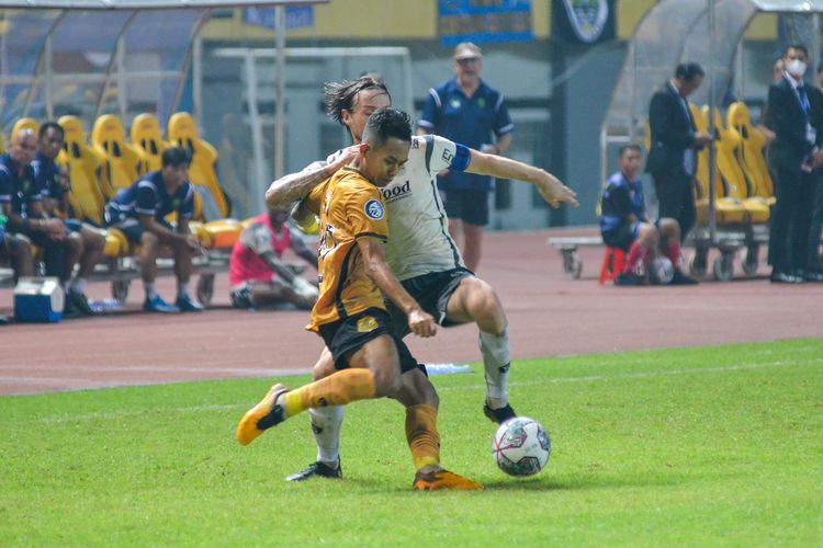 Sani Rizki Fauzi (kuning) menghalau bola yang hendak dikuasai Marc Klok (putih) dalam pertandingan pembuka Liga 1 2022-2023 antara Bhayangkara FC vs Persib Bandung, Minggu (24/7/2022) di Stadion Wibawa Mukti, Cikarang, Bekasi.