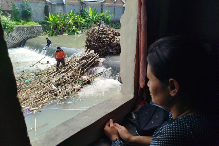 Siti Marfuati sedang melihat proses pembersihan rumpun bambu yang menyebabkan banjir di lingkungan rumahnya. 