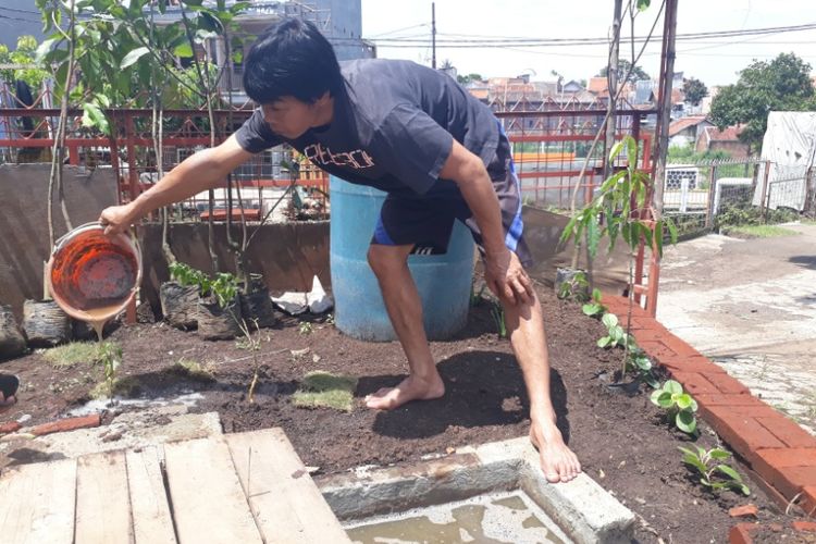 Emuh, pegawai pabrik tempe H Yoyo menyiram tanaman menggunakan air sisa  proses fermentasi limbah tempe menjadi biogas, Jumat (9/2/2018)
