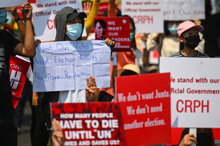 Para pengunjuk rasa memegang papan demo saat mereka melakukan demonstrasi menentang kudeta militer di depan Kedutaan Besar Indonesia di Yangon pada 23 Februari 2021. [Sai Aung Main/AFP]