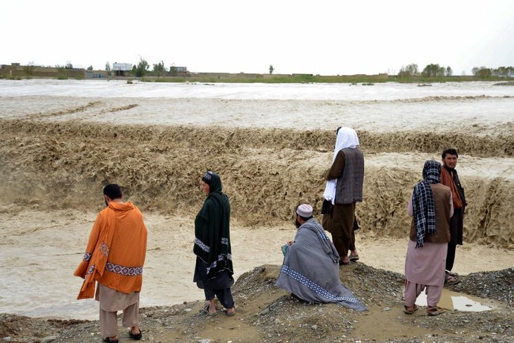 Warga Afghanistan menunggu untuk menyeberangi daerah banjir di distrik Spin Boldak di Provinsi Kandahar pada 13 April 2024, setelah banjir bandang menyusul hujan lebat.