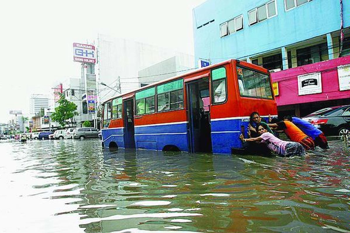 Warga membantu mendorong bus yang mogok akibat menembus genangan air di Jalan H Agus Salim, Jakarta Pusat, Kamis (12/11). Hujan deras yang mengguyur Jakarta menyebabkan sejumlah daerah tergenang.
