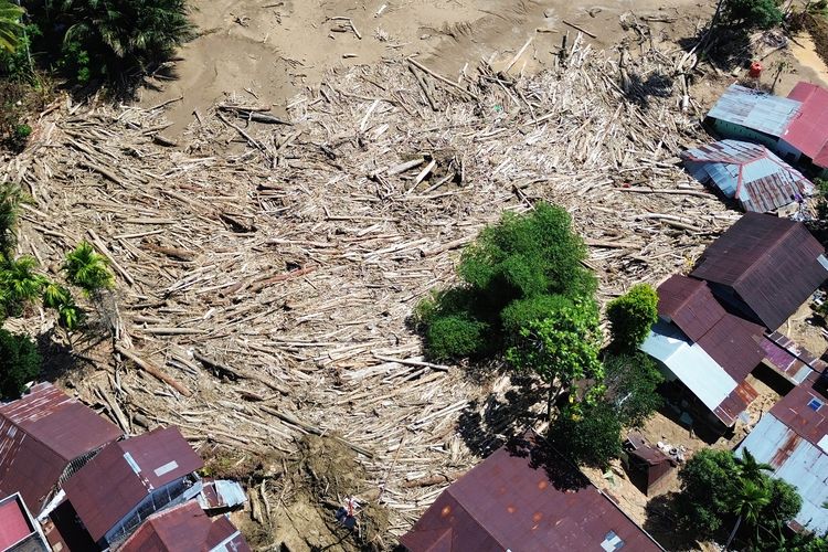 Foto udara tumpukan gelondongan kayu di permukiman di Tabiang Bandang Gadang, Nanggalo, Padang, Sumatera Barat, Selasa (9/12/2025). Gelondongan kayu yang terbawa banjir bandang sejak dua pekan lalu masih tersangkut di wilayah itu.  