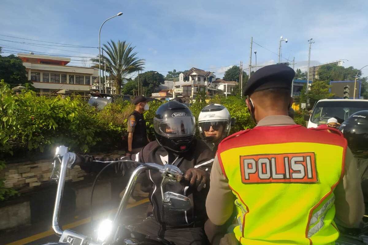 Seorang petugas dari kepolisian sedang memeriksa salah satu rombongan motor gede atau moge saat melintasi kawasan Puncak Bogor, Jawa Barat, pada Jumat (12/2/2021).