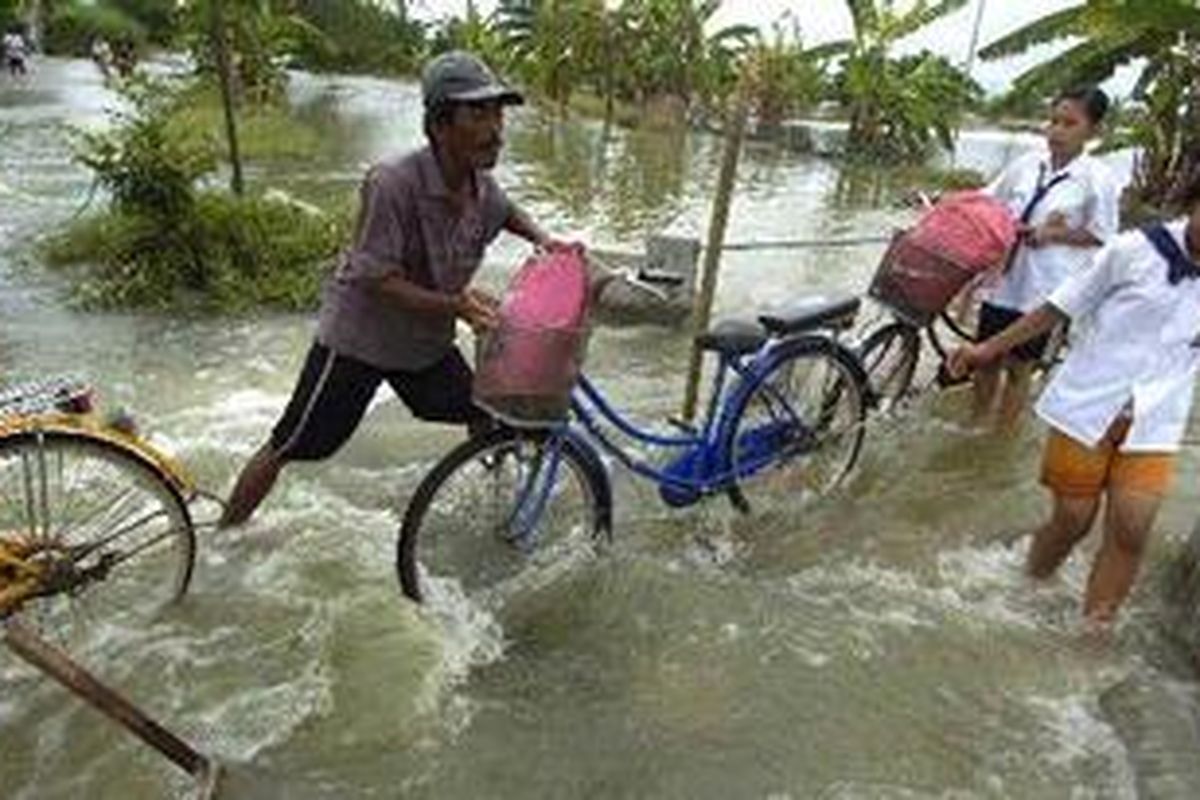 Warga melintasi arus deras luapan Kali Lamong di Kelurahan Sumberejo, Kecamatan Benowo, Kota Surabaya, Jawa Timur, Selasa (1/2/2011). Banjir dari luapan Kali Lamong juga menggenangi 38 desa di lima kecamatan di Gresik. Satu orang tewas tenggelam dalam musibah tersebut.