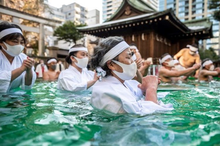 Umat Shinto di Kuil Teppou Zu Inari mandi dengan air dingin untuk menyucikan jiwa dan raga mereka selama ritual Tahun Baru di Tokyo pada 9 Januari 2022. 
