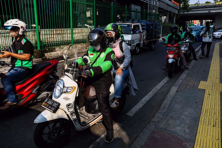 Pengemudi ojek online dengan penumpangnya melintas di Kawasan Stasiun Sudirman, Jakarta Pusat, Senin (8/6/2020). Pemerintah Provinsi DKI Jakarta mengizinkan pengemudi ojek online beroperasi untuk mengangkut penumpang selama PSBB transisi dengan menerapkan protokol kesehatan.