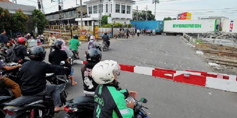 Pengendara sepeda motor berhenti di pintu pelintasan kereta api sebidang Pasar Senen, Jakarta Pusat, Selasa (27/9). Uji coba penutupan pelintasan kereta api sebidang di Pasar Senen mulai diberlakukan pada 1 Oktober. 