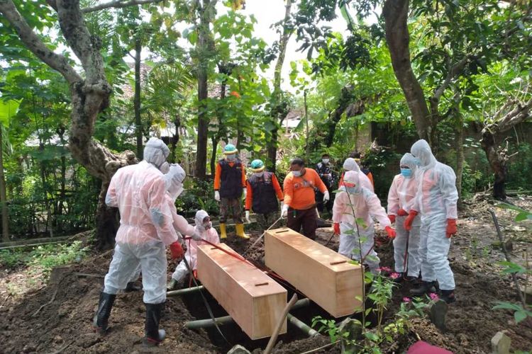 DIMAKAMKAN-- Dua jenazah pasien yang meninggal terpapar corona dimakamkan dalam satu liang lahat di Desa Munggu, Kecamatan Bungkal, Kabupaten Ponorogo, Jawa Timur, Senin (5/4/2021).