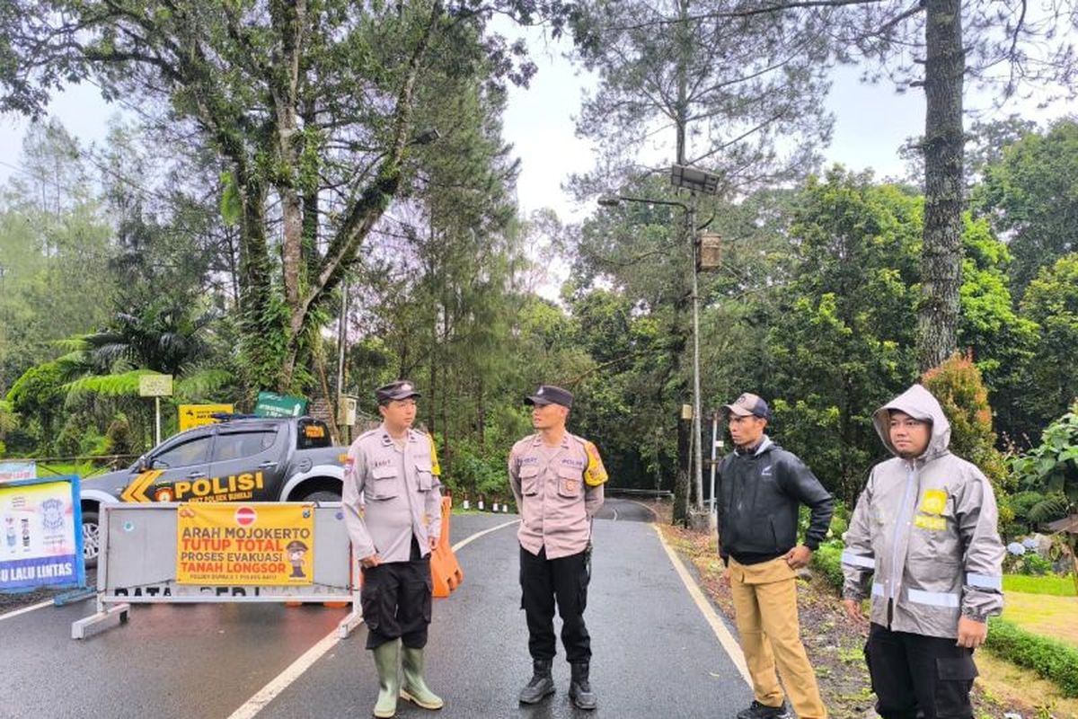 Petugas kepolisian berjaga di Jalur Cangar dari sisi Kota Batu, Jawa Timur saat penutupan jalur menuju Kabupaten Mojokerto akibat peristiwa tanah longsor di Kutukan Sendi, Pacet, Mojokerto, Senin (24/11/2025). 