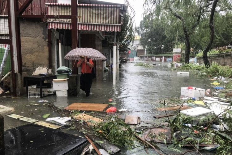 Seorang pria berjalan di tengah banjir di desa Lei Yu Man, setelah siklon tropis Mangkhut di Hong Kong pada Minggu (16/9/2018). (AFP/Anthony Wallace)