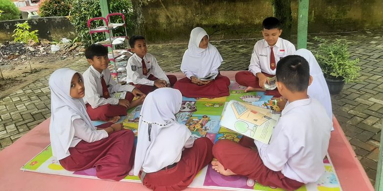 Aktivitas siswa membaca buku bersama di sekolah untuk meningkatkan literasi anak.