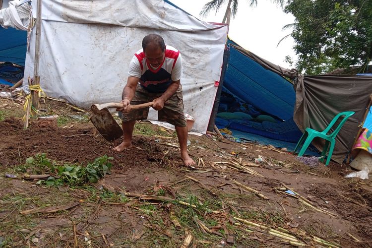 Seorang pengungsi di Kampung Warungbatu, Kecamatan Cianjur, Cianjur, tengah membuat parit di sekeliling tenda darurat untuk mencegah banjir saat hujan turun.