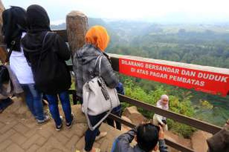 Pengunjung melompati dan bersandar di pagar pembatas di Tebing Keraton, Bandung, Minggu (10/7/2016). Hal ini sebenarnya terlarang, namun banyak pengunjung melanggar. 