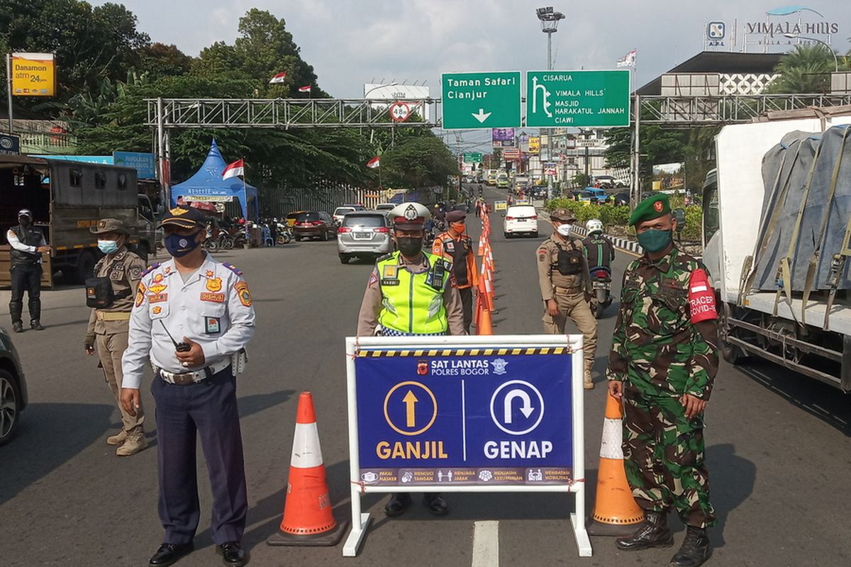 Petugas gabungan sedang menjaga pos pemeriksaan ganjil genap di Simpang Gadog, Kecamatan Ciawi, Kabupaten Bogor, Jawa Barat.