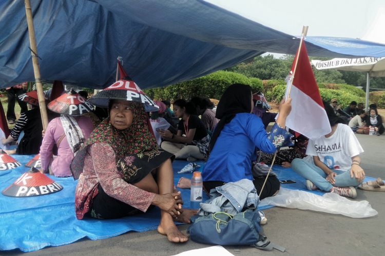 Belasan petani asal kawasan Pegunungan Kendeng, Jawa Tengah, menggelar aksi protes terkait keberadaan pabrik semen di atas sumber mata pencaharian mereka.  Warga Kendeng yang sebagian besar terdiri dari kaum perempuan itu mendirikan tenda beratapkan terpal berwarna biru di seberang Istana Kepresidenan, tepatnya di silang barat Monas, Jakarta Pusat, Senin (4/9/2017).  Sebanyak tujuh bendera Merah Putih dikibarkan di setiap tiang tenda tersebut. Sementara, para petani Kendeng dan sejumlah aktivis HAM berteduh di dalam tenda.  Koordinator aksi, Joko Santoso mengatakan, aksi tersebut merupakan sebuah bentuk protes warga Kendeng terhadap keberadaan pabrik PT Semen Indonesia yang masih terus beroperasi, kendati proses Kajian Lingkungan Hidup Strategis (KLHS) tahap II masih berjalan.  Pasalnya, Presiden Joko Widodo memerintahkan penghentian kegiatan pabrik semen di kawasan Pegunungan Kendeng selama proses KLHS berjalan.