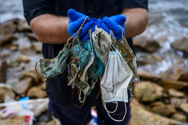 Foto tertanggal 13 Mei 2020 menunjukkan Gary Stokes pendiri LSM lingkungan hidup Oceans Asia, memegang sampah masker sekali pakai yang berserakan di Discovery Bay di Pulau Lantu yang terpencil di Hong Kong. Selain berserakan di sepanjang garis pantai, beberapa sampah masker sekali pakai juga hanyut ke laut.