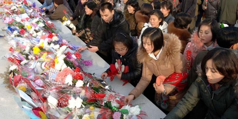 Warga Korea Utara menaruh karangan bunga di depan patung Kim Il Sung dan putranya, Kim Jong Il dalam peringatan dua tahun kematian ayah Kim Jong Un itu pada Selasa (17/12/2013) di Pyongyang.