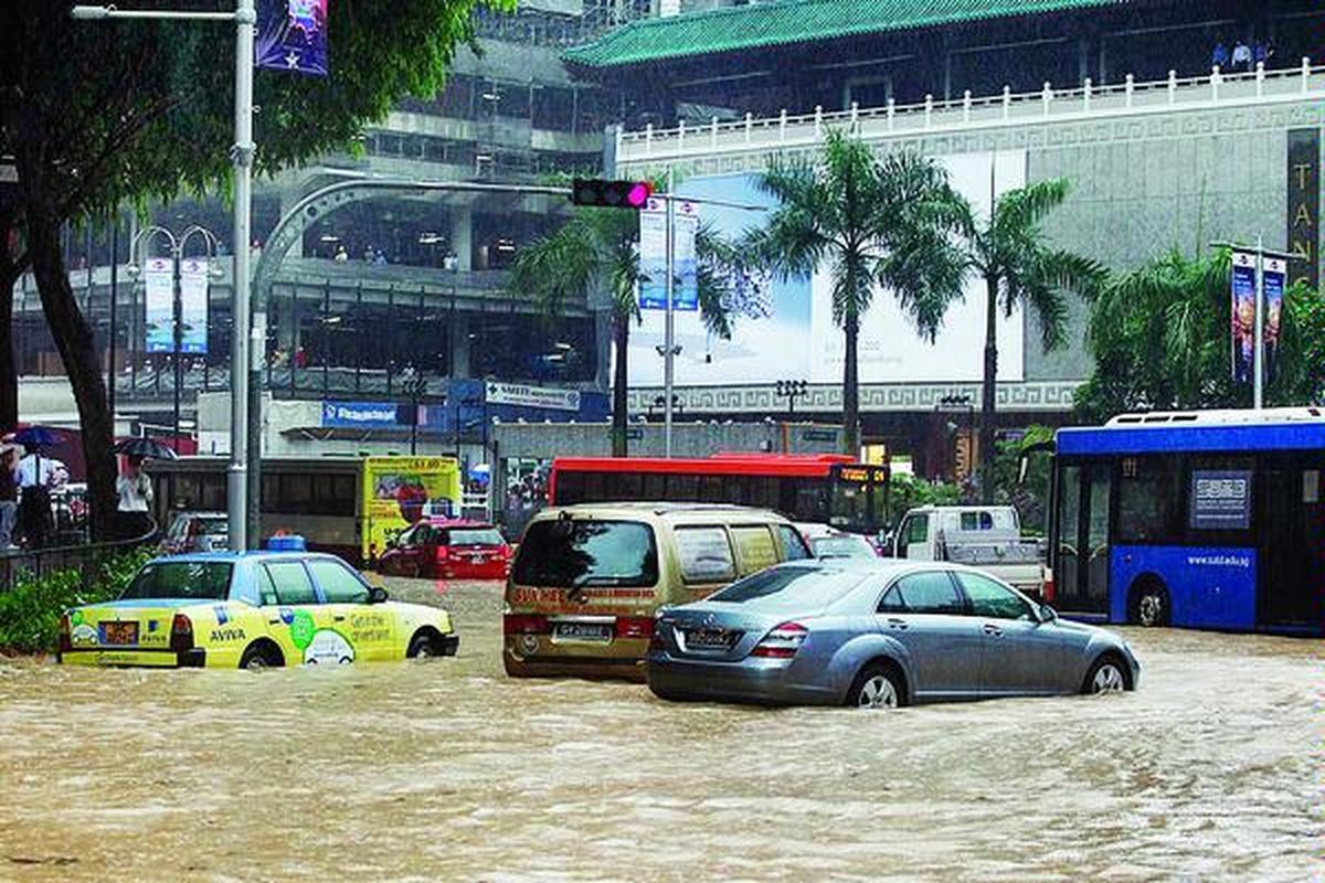 Sedan mewah dan kendaraan lain mogok di tengah banjir di Orchard Road, Singapura, Rabu (16/6).