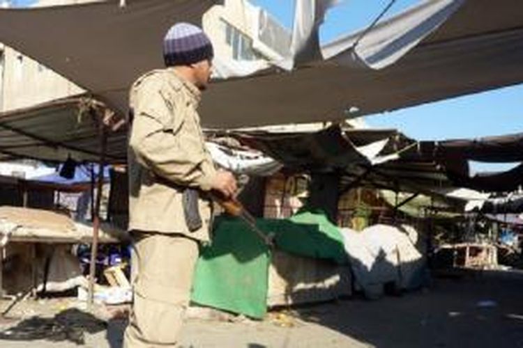 Petugas keamanan berjaga di luar sebuah pasar dekat gereja St. John di Distrik Dora, Baghdad, yang menjadi target pengeboman, Rabu (25/12/2013).