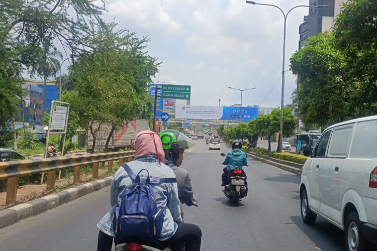 Pengendara motor yang sedang berboncengan tanpa menggunakan helm saat melintas di Jalan Ahmad Yani, Pekayon, Bekasi Selatan, Senin (31/10/2022). Sejak penindakan tilang manual ditiadakan, banyak ditemukan pelanggaran saat berkendara terutama para pengendara sepeda motor.