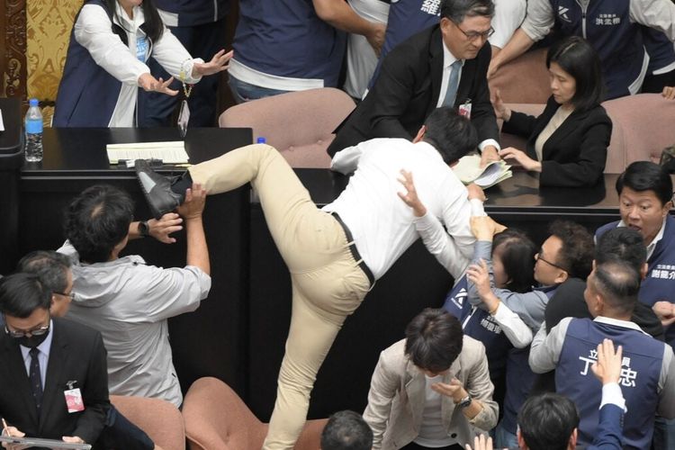 Anggota parlemen Taiwan Kuo Kuo Wen (tengah) mencoba melompat ke meja. Anggota parlemen Taiwan dari partai berkuasa dan oposisi terlibat dalam perkelahian fisik, seperti saling pukul dan tendang, maupun serangan verbal saat rapat pada Jumat (17/5/2024).