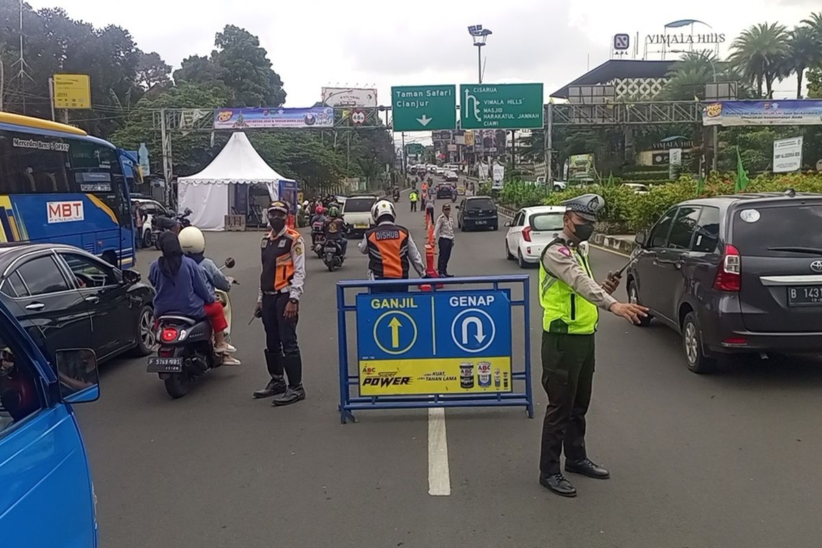 Petugas kepolisian sedang melakukan pengaturan skema ganjil genap di kawasan wisata Puncak Bogor, Jawa Barat.