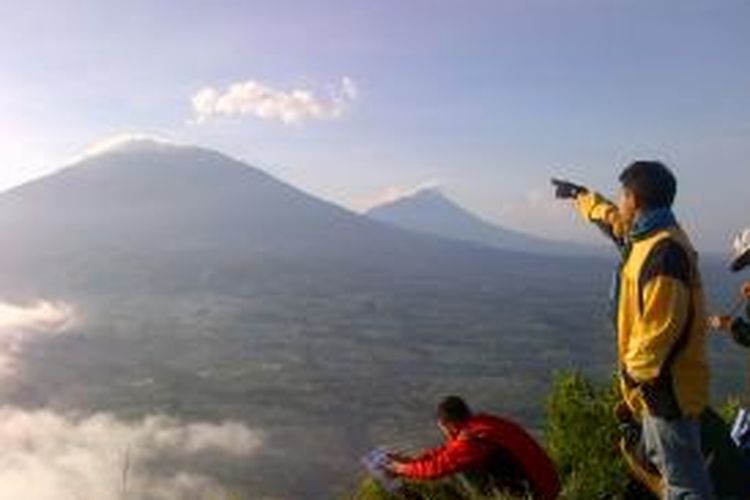 (2) Salah seorang pendaki menunjukkan Gunung Merbabu dan Gunung Merapi tepat di atas mahatari itu terbit, Minggu (5/4/2015) pagi.