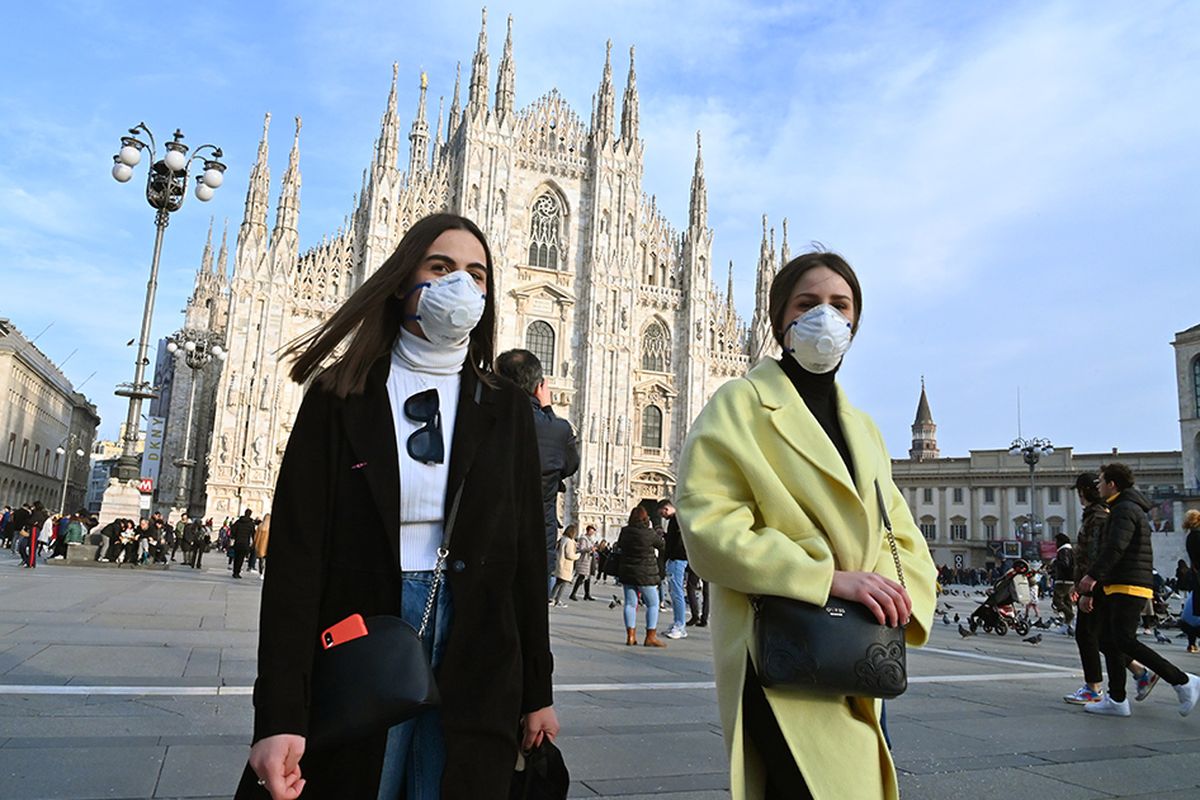 Warga mengenakan masker wajah guna mengantisipasi penyebaran virus corona saat berjalan melintasi Piazza del Duomo di Milan, Italia, Minggu (23/2/2020). Penyebaran virus corona hingga hari ini, Senin (24/2/2020), semakin menunjukkan peningkatan di sejumlah negara, seperti Italia, Iran, dan Korea Selatan.