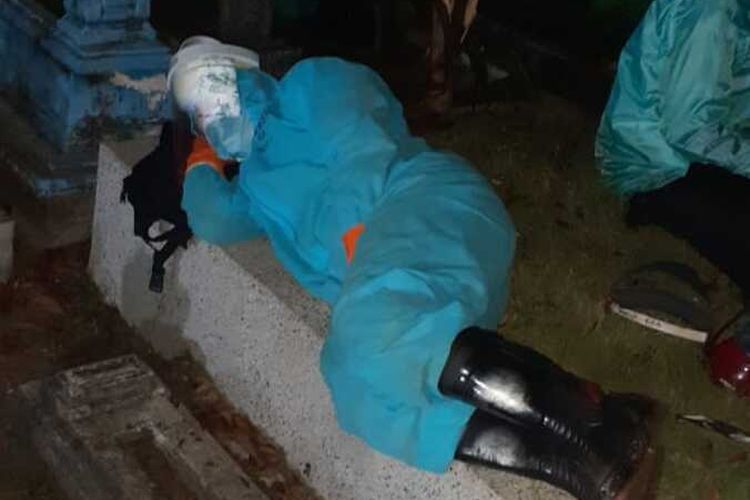 Seorang relawan pemakaman jenazah Covid-19 tertidur di kuburan