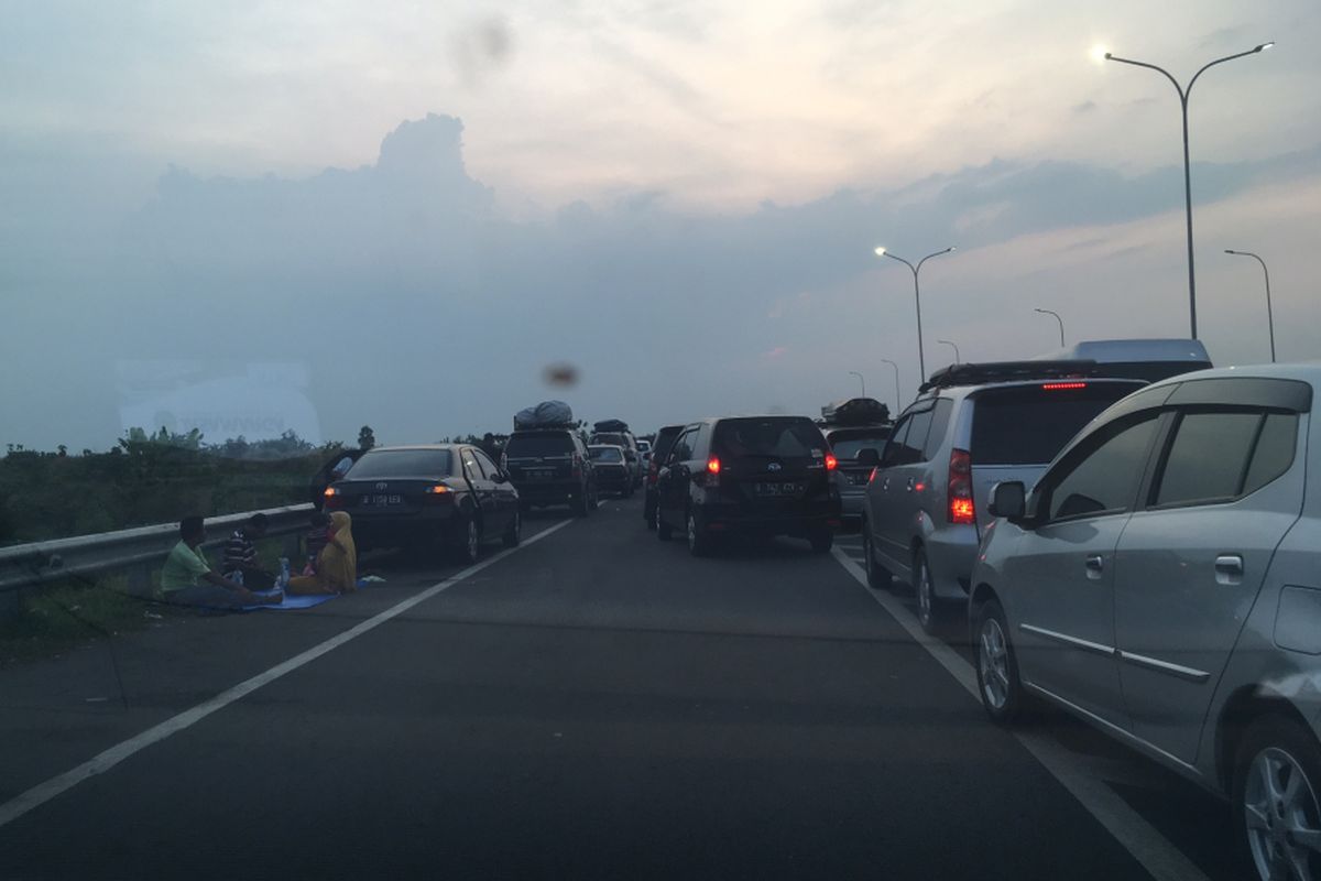 Sejumlah pemudik memilih menepikan kendaraan dan beristirahat di bahu jalan Tol Cipali, Sabtu (1/7/2017) petang. Semua tempat istirahat (rest area) di tol ini di arah menuju Jakarta penuh sesak dan tak bisa menampung lagi pelintas yang belakangan datang.