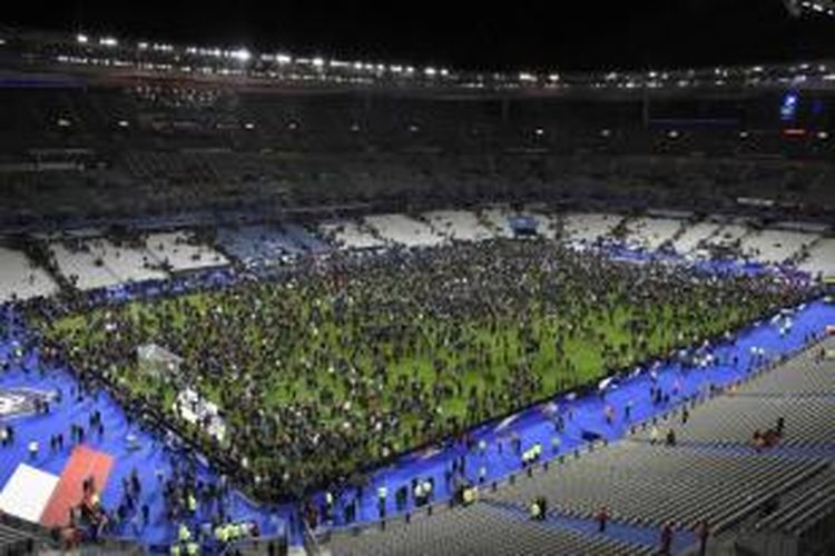 Penonton laga persahabatan antara Perancis melawan Jerman berkumpul di tengah lapangan seusai mendengar suara ledakan dekat stadion Stade de France, Paris, 13 November 2015. Lebih dari 100 orang tewas dalam aksi penembakan dan bom yang dilakukan oleh teroris pada 13 November malam.
