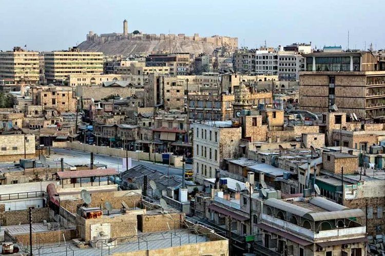 Kota Aleppo, Suriah, dengan benteng abad pertengahan di latar belakang ddan arsitektur rumah Timur Tengah. 