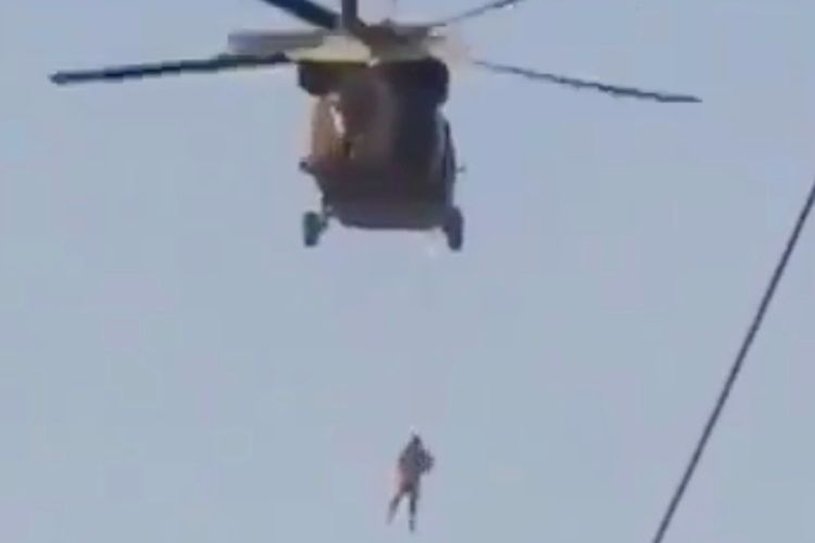 Seseorang yang terlihat digantung di bawah helikopter Black Hawk yang sedang dioperasikan oleh Taliban. [Twitter/@TalibTimes Via New York Post]