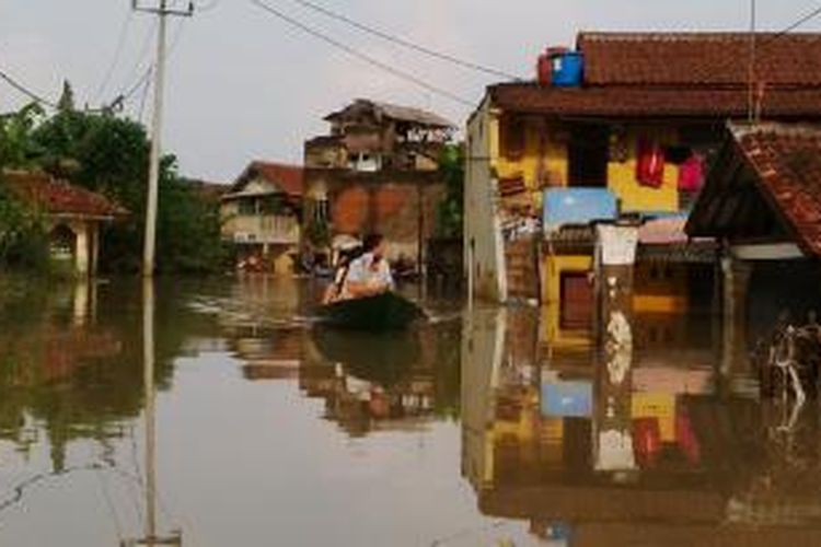 Warga terlihat menaiki perahu di lokasi yang terendah banjir di kampung Cieunteung, Kelurahan Baleendah, Kecamatan Baleendah, Kabupaten Bandung, Jawa Barat, Minggu, (21/12/2014)