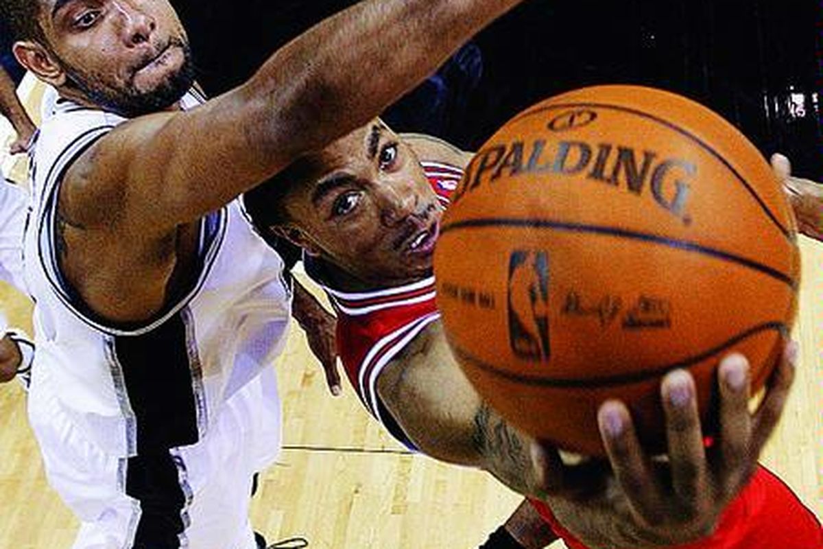 Pemain Chicago Bulls, Derrick Rose (kanan), menerobos pertahanan pemain San Antonio Spurs, Tim Duncan, dalam laga NBA di San Antonio, Amerika Serikat, Rabu (17/11). Spurs menang 103-94.