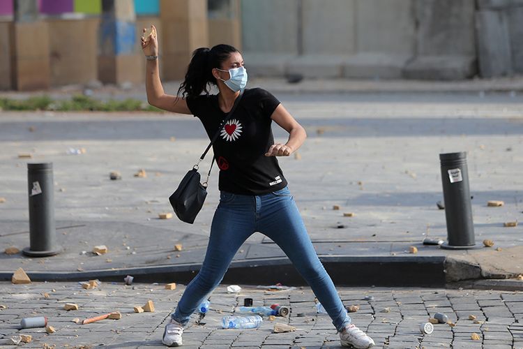 Seorang pengunjuk rasa wanita melemparkan batu ke arah aparat keamanan saat demo berujung ricuh menyusul protes ledakan yang terjadi Selasa lalu, di pusat kota Beirut, Lebanon, Sabtu (8/8/2020). Unjuk rasa tersebut merupakan bentuk kemarahan warga kepada pemerintah Lebanon yang dianggap lalai, menyusul ledakan besar di Beirut pada 4 Agustus lalu yang merenggut ratusan korban jiwa.