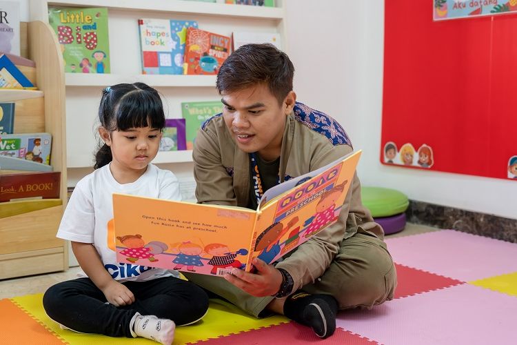 Guru sedang membantu anak didik belajar.