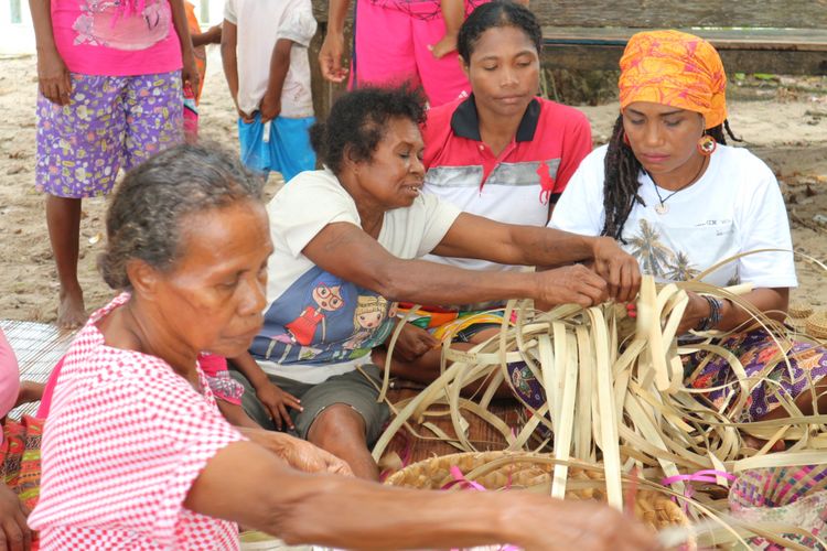 Kaka Yeni (kanan), dan mamak-mamak yang tergabung dalam komunitas Mamak Noken belajar membuat beragam kerajinan dari bahan dedaunan, terutama noken di Kampung Sauwingrai, Raja Ampat, Papua Barat.