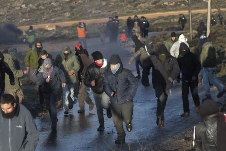 Para pemukim Yahudi berlarian dalam bentrokan dengan pasukan keamanan Israel yang mengevakuasi permukiman ilegal Amona di Tepi Barat, Rabu (1/2/2017).