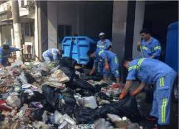 Para pekerja kebersihan di kota Shanghai, China ini mengaduk tumpukan sampah untuk mencari telepon genggam milik seorang turis.
