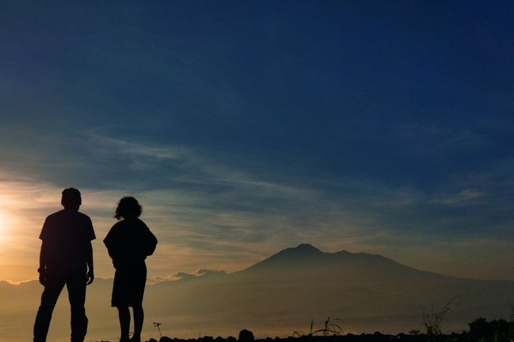 Dua orang wisatawan tengah menikmati pemandangan Gunung Gede Pangrango saat momen golden sunrise yang dilihat dari Desa Pasirjaya, Kecamatan Cigombong, Kabupaten Bogor pada Kamis (27/5/2021).