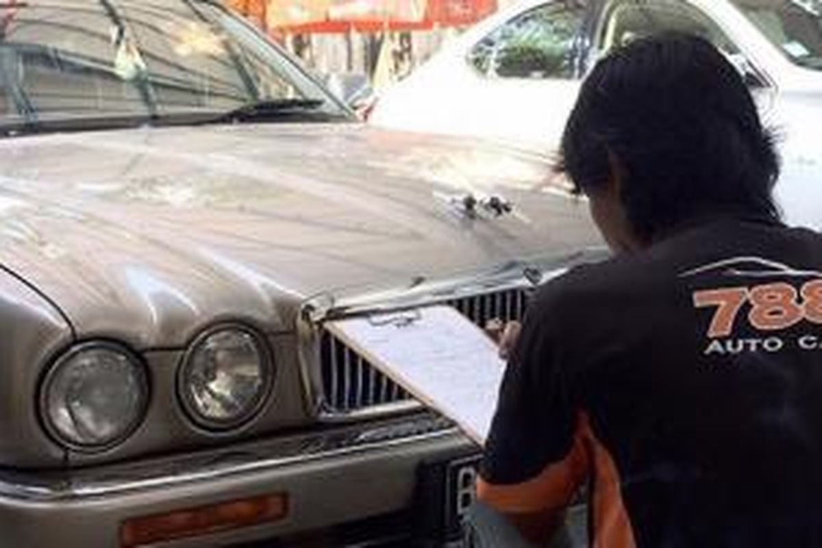 Salah satu pegawai 788Autocare sedang melihat bodi mobil konsumen yang akan dipoles.