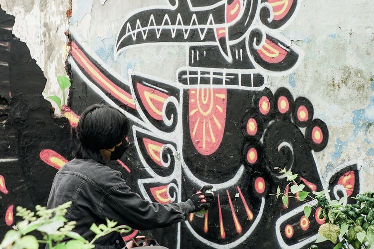 Yoga menggambar sebuah mural di daerah Sompok, Lamper Lor, Semarang Selatan. (Dok. Yoga)