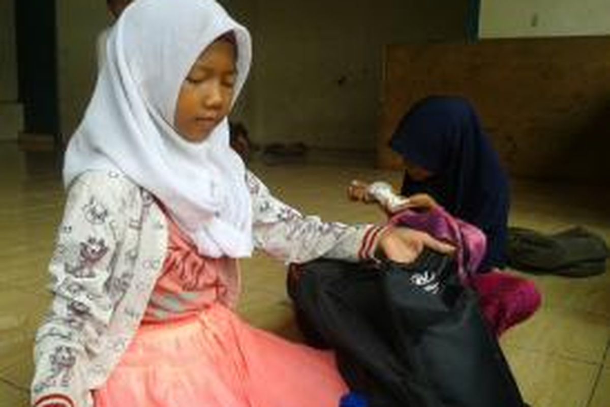 Yani, siswa kelas 5 Sekolah Master, memasukkan barang dagangan ke tas sekolahnya, Senin (14/9/2015). Siswa berusia 11 tahun itu menjadi tulang punggung keluarga karena kedua orangtuanya sakit.